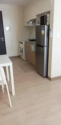 a kitchen with a refrigerator and a table and a microwave at The Verdin Brand-New Unit with Pool, Gym, & High-Speed Wi-fi in General Trias