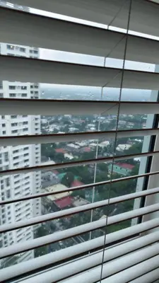 a view of a city through the blinds of a window at Studio Premier Suite Makatii by Christine Suites PH in Manila