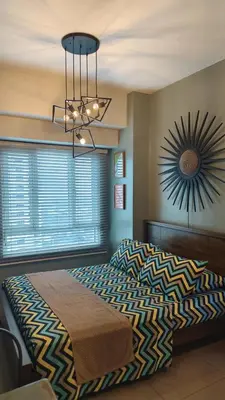 a bedroom with a large bed and a clock on the wall at Studio Premier Suite Makatii by Christine Suites PH in Manila