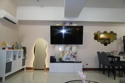 a living room with a tv hanging on the wall at Modern Rustic Pet Friendly Condo in Mckinley Hill BGC in Manila