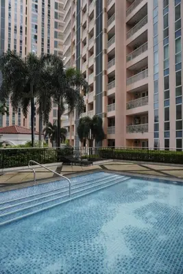 a swimming pool in a building with palm trees at Modern Rustic Pet Friendly Condo in Mckinley Hill BGC in Manila