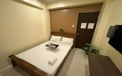 a small room with a bed and a door at San Antonio's Place Suites in Manila