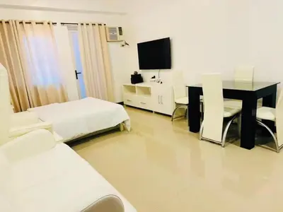 a room with two beds and a desk and a television at Cozy Studio in Paraaque - Perfect for Transients and Long-Stayers Alike in Manila