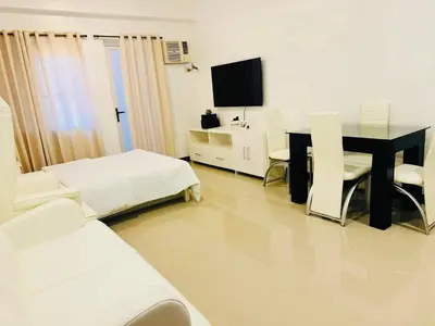 a living room with a table and a tv at Cozy Studio in Paraaque - Perfect for Transients and Long-Stayers Alike in Manila