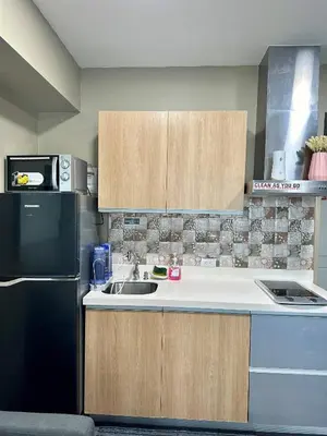 a kitchen with a sink and a black refrigerator at Condo near airport with PS4 and Parking in Manila