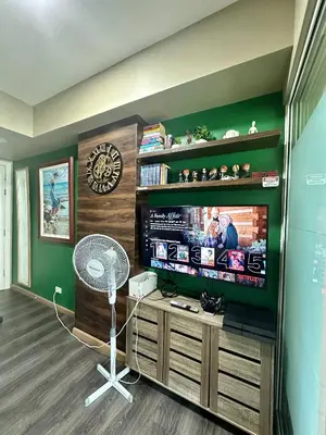 a living room with a flat screen tv and a fan at Condo near airport with PS4 and Parking in Manila