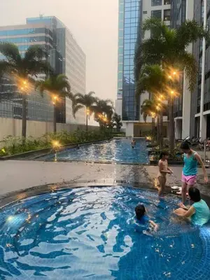 a group of people in a swimming pool in a city at One Eastwood with mountain view in Manila
