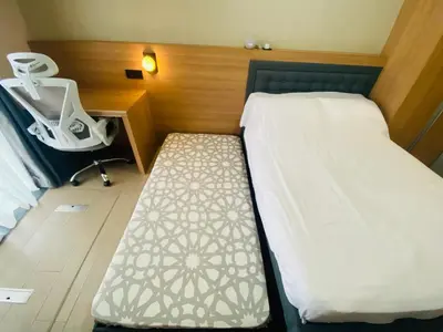 a bedroom with a bed with a chair and a desk at One Eastwood with mountain view in Manila