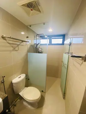 a bathroom with a toilet and a glass shower at One Eastwood with mountain view in Manila