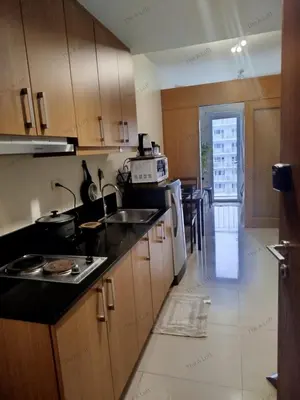 a kitchen with wooden cabinets and a counter top at Classy and Cozy Staycation near MOA in Manila