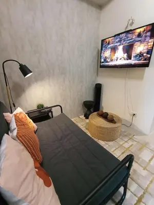 a living room with a table and a tv at Classy and Cozy Staycation near MOA in Manila