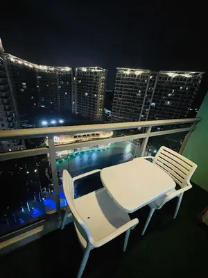 a table and chairs on a balcony with a city skyline at B&T Azure Staycation - Parañaque in Manila