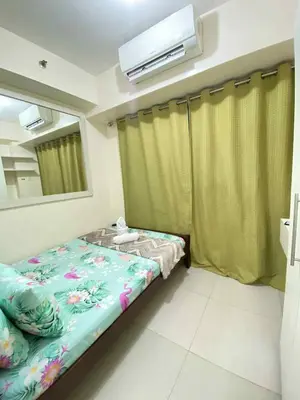 a small room with a bed and a mirror at The Tenth Balcony in Manila