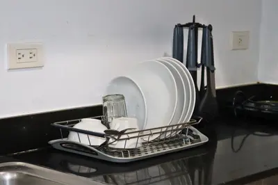a dish drying rack with plates and cups on a kitchen counter at Niu Ohana Ortigas Apartments and Residences in Manila