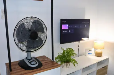 a black fan sitting on a table next to a tv at Niu Ohana Ortigas Apartments and Residences in Manila