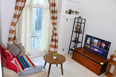 a living room with a tv and a couch and a table at Niu Ohana Ortigas Apartments and Residences in Manila