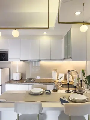 a kitchen with white cabinets and a table with chairs at Casa Elisae l Venice Grand Canal Mall Access in Manila