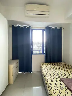 a bedroom with a bed with blue curtains and a window at AilynSea residence staycation in Manila