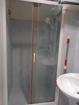 a shower with a glass door next to a sink at AilynSea residence staycation in Manila