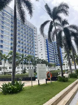 a sign in front of a large building with palm trees at AilynSea residence staycation in Manila