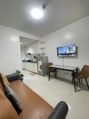 a living room with a table and a kitchen at AilynSea residence staycation in Manila