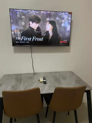 a table with two chairs and a tv on the wall at AilynSea residence staycation in Manila