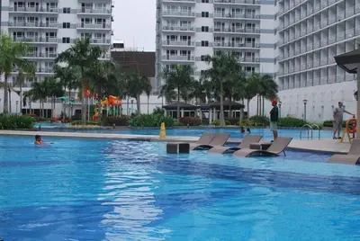 a large swimming pool with chairs and buildings at 349B by Premiere Haven Shell Residences in Manila