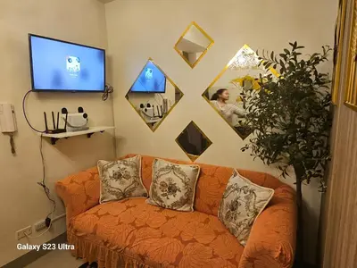 a living room with an orange couch and a tv at Staycation near MOA, SMX Convention, DFA & NAIA, in Manila