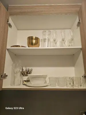 a cupboard with glasses and plates and a bowl at Staycation near MOA, SMX Convention, DFA & NAIA, in Manila