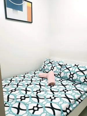 a bed with a black and blue comforter at Shore 3 Residences Condo with Netflix and Wifi in Manila