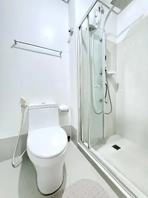 a white bathroom with a toilet and a shower at SMDC Light Residences - Studio Condo Unit in Manila
