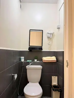 a bathroom with a toilet and a mirror on a shelf at Mars Condo Unit in Manila