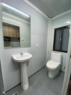 a white bathroom with a toilet and a sink at Sunrise Dormitel in Manila