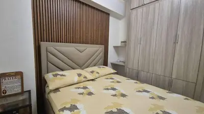 a small bedroom with a bed with a large headboard at JeweIs Homey Place -2br in a resort-like condo in Manila