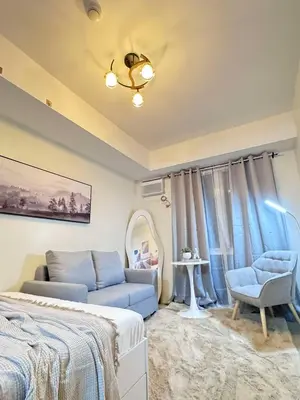 a bedroom with a bed and a couch and a chair at Queen's Escape in Manila