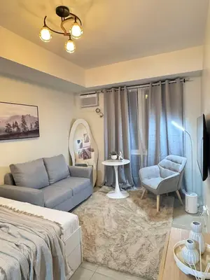 a bedroom with a bed and a couch and a table at Queen's Escape in Manila