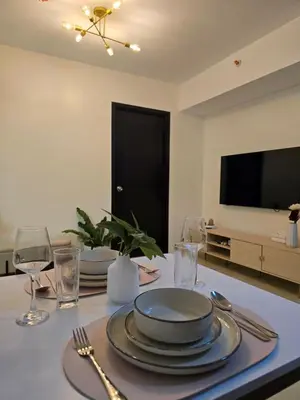 a dining room table with plates and glasses and a television at Queen's Escape in Manila