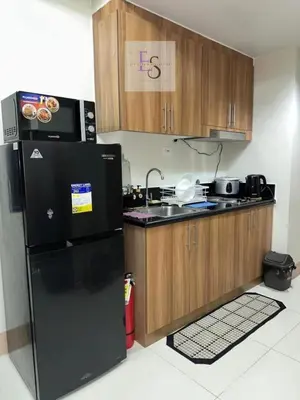 a kitchen with a black refrigerator and wooden cabinets at EyaLove's Staycation in Manila