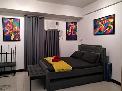 a bedroom with a couch and paintings on the wall at RER-101 Newport Boulevard, Pasay City, Metro Manila, Philippines near NAIA Terminal 3 in Manila