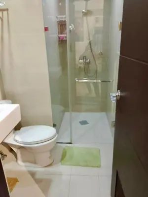 a bathroom with a shower with a toilet and a green rug at RER-101 Newport Boulevard, Pasay City, Metro Manila, Philippines near NAIA Terminal 3 in Manila