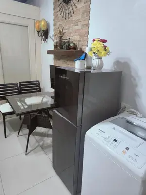 a kitchen with a refrigerator and a table and a microwave at SEA RESIDENCES CONDOTEL by Tvans in Manila