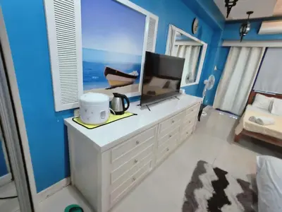 a bedroom with blue walls and a tv on a dresser at SEA RESIDENCES CONDOTEL by Tvans in Manila