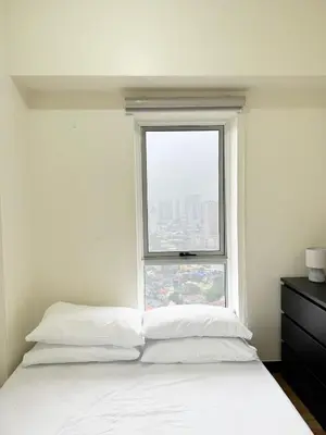 a bedroom with a white bed and a window at Corner 37 at Lumiere Residences in Manila