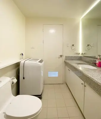 a white bathroom with a toilet and a sink at Corner 37 at Lumiere Residences in Manila