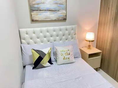 a bedroom with a white bed with pillows at SMDC Coast Residence in Manila