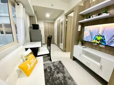 a living room with a tv and a white couch at SMDC Coast Residence in Manila