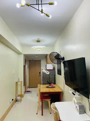 a living room with a table and a television at Stylish and Cozy Condo Near Mall of Asia in Manila