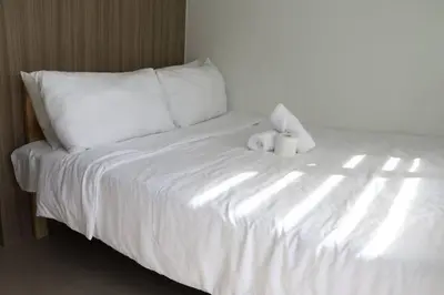 a white bed with two stuffed animals sitting on it at The Nuebe Chalet near SM Moa Pasay City in Manila