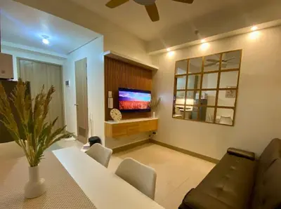 a living room with a tv and a table and chairs at The Nuebe Chalet near SM Moa Pasay City in Manila