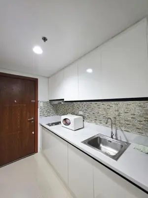 a kitchen with white cabinets and a sink and a door at Bellas Place Shell Residences MOA in Manila